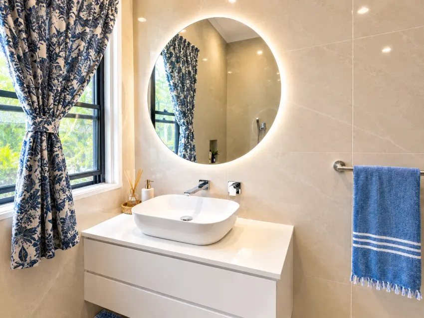 Bathroom vanity with round illuminated mirror and blue towels at Margate Getaway