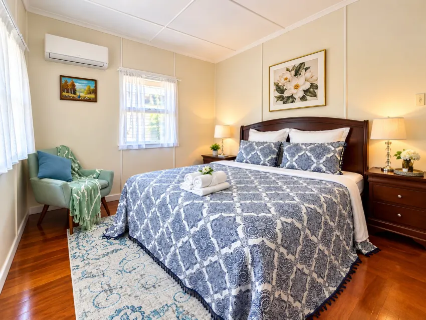 Bedroom with blue patterned linen, timber floors and a green armchair at Margate Getaway