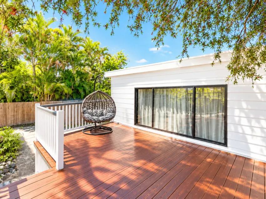 Sunlit timber deck with hanging egg chair and garden at Margate Getaway