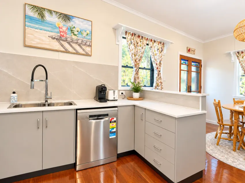 Bright kitchen with white cabinetry and dining nook at Margate Getaway